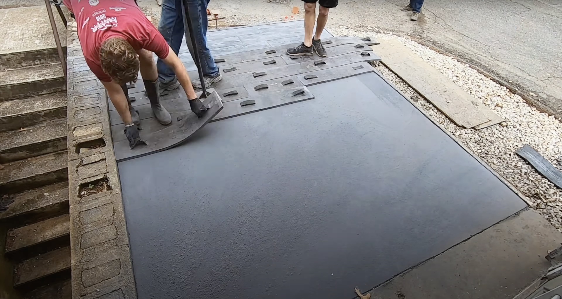 Professional stamped concrete installation with decorative pattern work Concrete contractor using stamping tools for decorative pattern installation